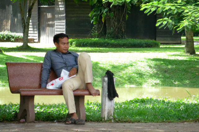 Homme sur un banc dans un parc au Cambodge.